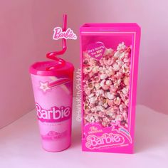 a pink cup with a straw next to it in front of a box of popcorn