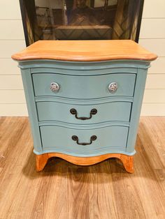 a blue dresser with two drawers in front of a fireplace