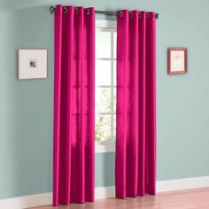 pink curtains hanging on the side of a window in a room with hardwood floors and blue walls