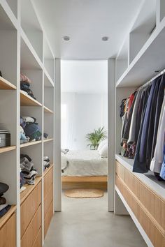 a walk in closet with lots of clothes hanging on the walls and shelves next to it