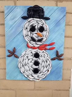 a snowman made out of rope on the side of a building with a cowboy hat