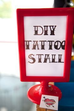 a sign that says diy tattoo stall on top of a red stand with scissors