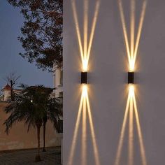 two wall lights on the side of a building with palm trees in front of them