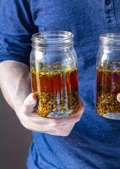 two jars filled with different colored liquid in each one, held by someone's hands