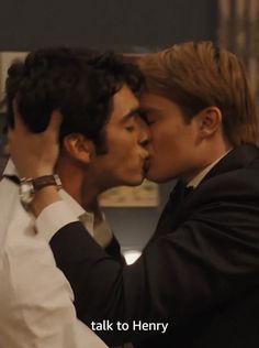 two young men kissing each other while wearing suits