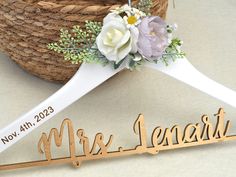 a wooden name hanger with flowers on it