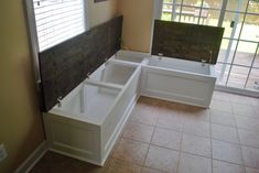 a bathroom with two sinks and a bathtub in the corner, next to a sliding glass door