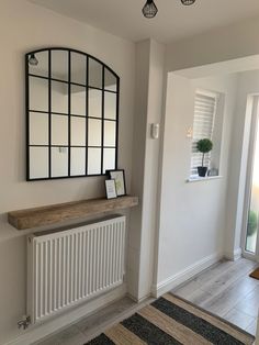 a hallway with a mirror, radiator and wooden bench on the side wall