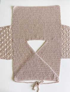 a crocheted piece of cloth on top of a white surface with a hole in the middle