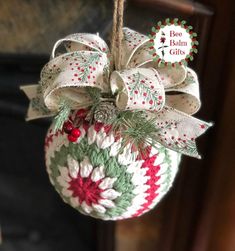 a christmas ornament hanging from a rope with a bow and holly on it