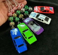 there are many different toy cars on the table next to each other, and one is being held by someone's hand