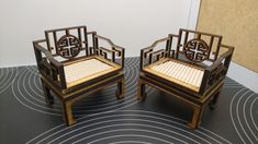 two wooden chairs sitting next to each other on top of a black and white floor