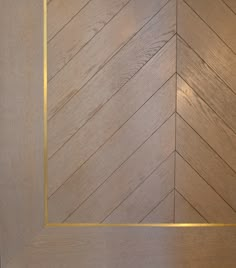 an empty wooden door with gold trim on the bottom and side panel, in a herringbone pattern