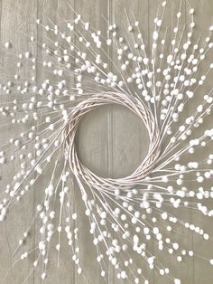 a wreath made out of white flowers on a wooden surface