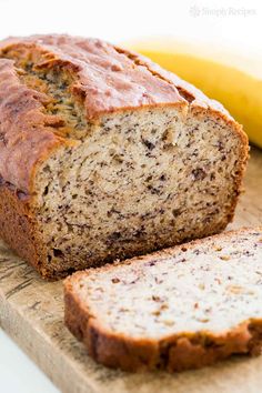 a loaf of banana bread sitting on top of a cutting board next to a ripe banana