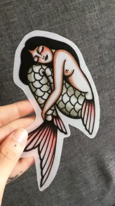 a person holding up a sticker with an image of a mermaid on it's back