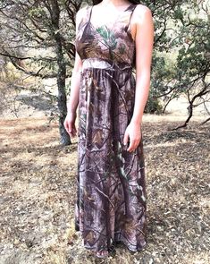 a woman wearing a camo dress standing in the grass with her hand on her hip