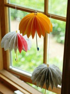 two paper flowers hanging from strings in front of a window