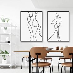 two abstract paintings hang on the wall above a dining room table with four brown chairs