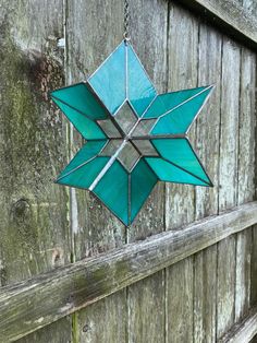 a stained glass star hanging on a wooden fence