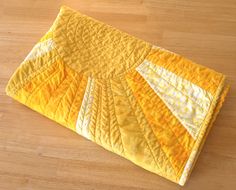 a yellow and white quilted placemat on a wooden floor with a wood surface