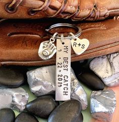 a baseball glove, mitt and keychain are sitting on some rocks