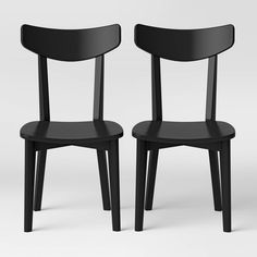 two black chairs sitting next to each other on a white surface with no one in it