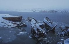 an old boat sitting on top of ice covered water next to another ship in the ocean