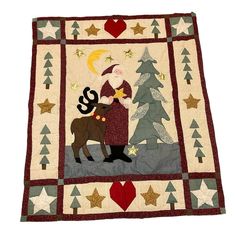 a quilted christmas scene with a woman and a reindeer in the snow, surrounded by trees