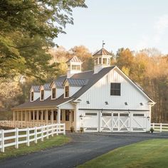 a white barn with a black roof and windows