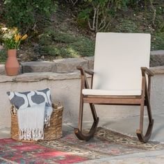 a white chair sitting on top of a rug next to a potted plant and basket