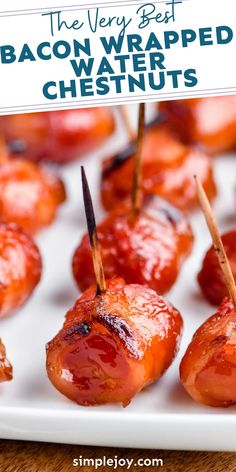 bacon wrapped water chestnuts with toothpicks in them on a white platter