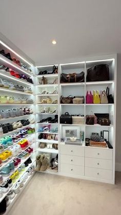 a large white closet filled with lots of shoes and handbags on shelves next to a doorway