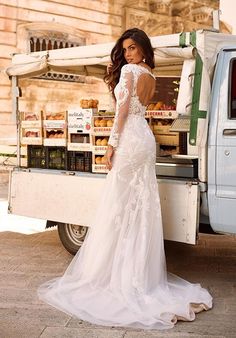 a woman in a wedding dress standing next to a food truck with donuts on the back