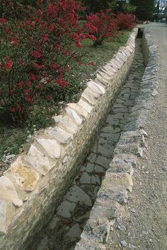 an old stone wall next to some flowers