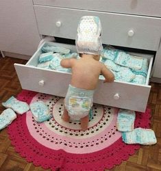 a small child in diapers is looking into a drawer