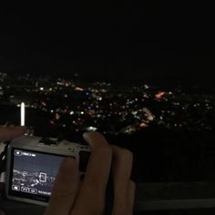 someone is taking a photo with their cell phone at night in front of the city lights