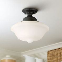 a light fixture in a room with white walls and ceiling fan on the right side