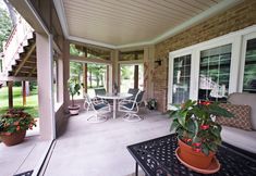 a patio with chairs, table and potted plants