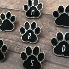 six black and silver dog paw magnets with the letter m, s, and d on them