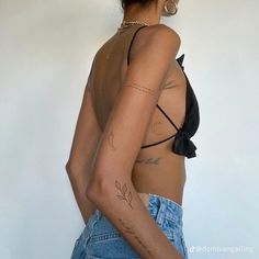 a woman with tattoos on her arm and chest standing in front of a white wall