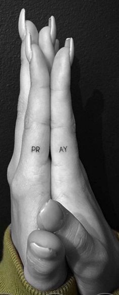 two hands holding each other with the words pray written on their fingers in black ink