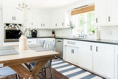 a kitchen with white cabinets and black counter tops is seen in this image from the dining room table