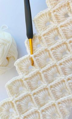 the crochet pattern is being worked on with a knitting needle and yarn ball