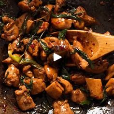 chicken and spinach stir fry in a wok with a wooden spoon on the side