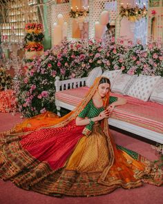 a woman sitting on top of a bed in a room filled with flowers and greenery