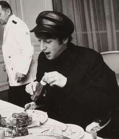 black and white photograph of a man cutting food at a table