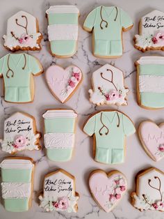 decorated cookies are arranged in the shape of doctors'shirts and medical scrubs on a marble surface