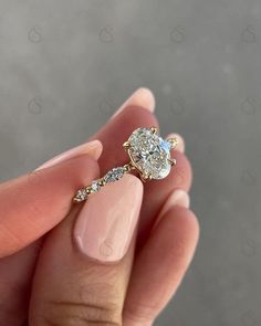 a woman's hand holding an engagement ring with a pear shaped diamond on it