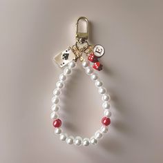 a white beaded keychain with red and white charms on it's side